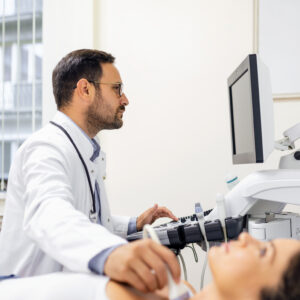 Endocrinologue masculin réalisant une échographie sur une patiente dans un cabinet d'ultrason.